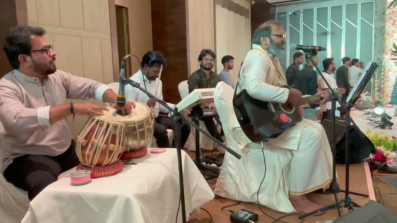 Hemant Acharya playing guitar and singing with a tabla player and keyboardist at a wedding