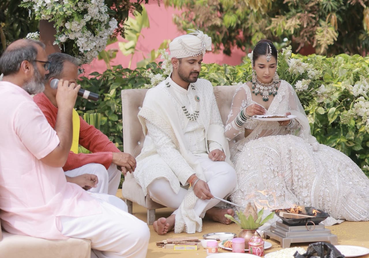 A bride and groom seated at the sacred fire during the pheras, offering into the agni